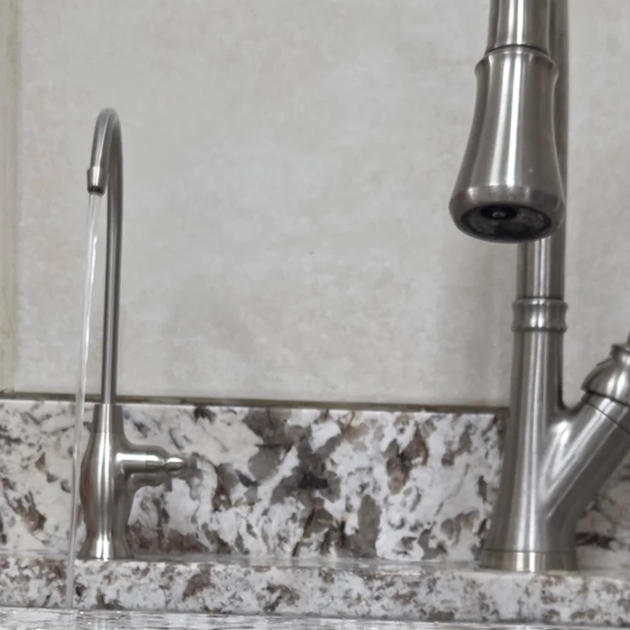 Clear drinking water beside a modern kitchen reverse-osmosis faucet